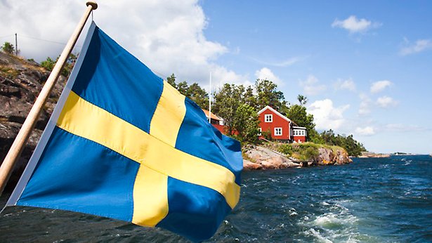 Svenska flaggan och skärgården en sommardag
